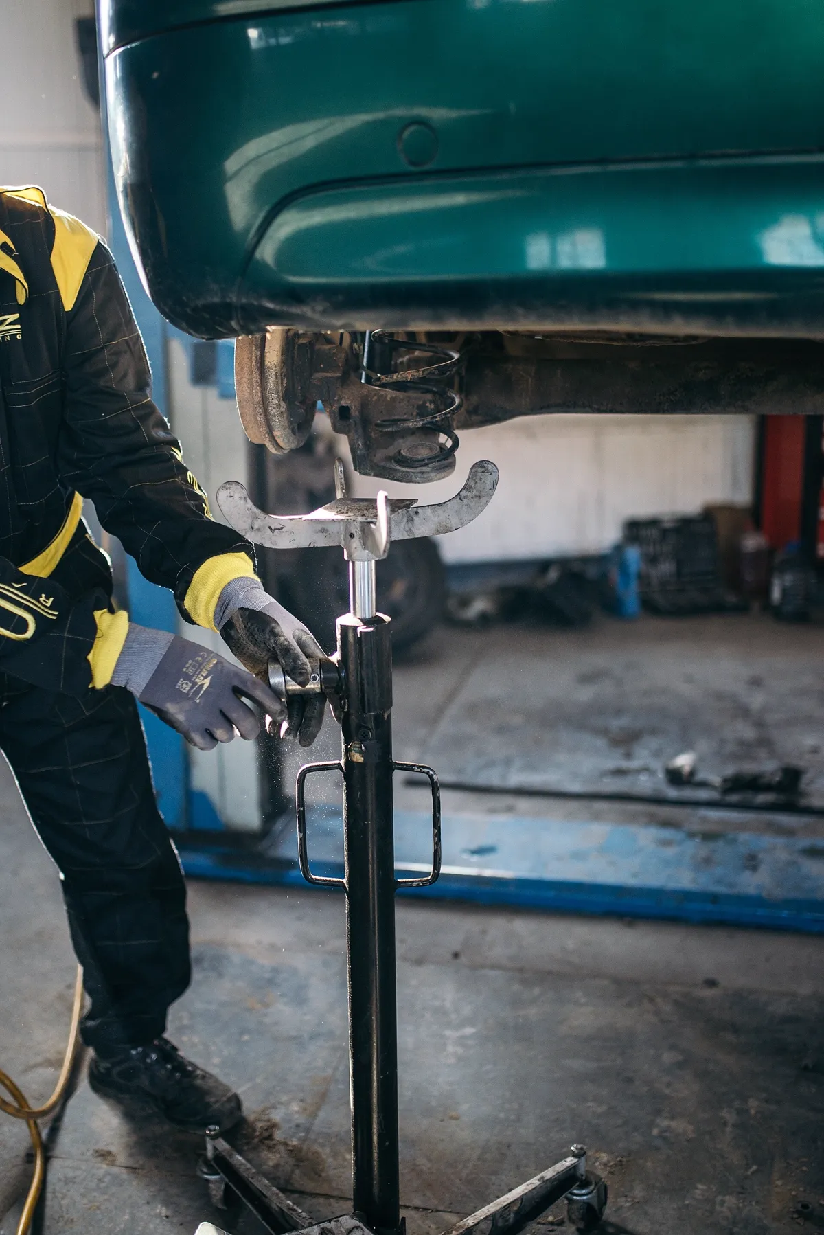 Technician adjusting a jack stand under a car on the lift